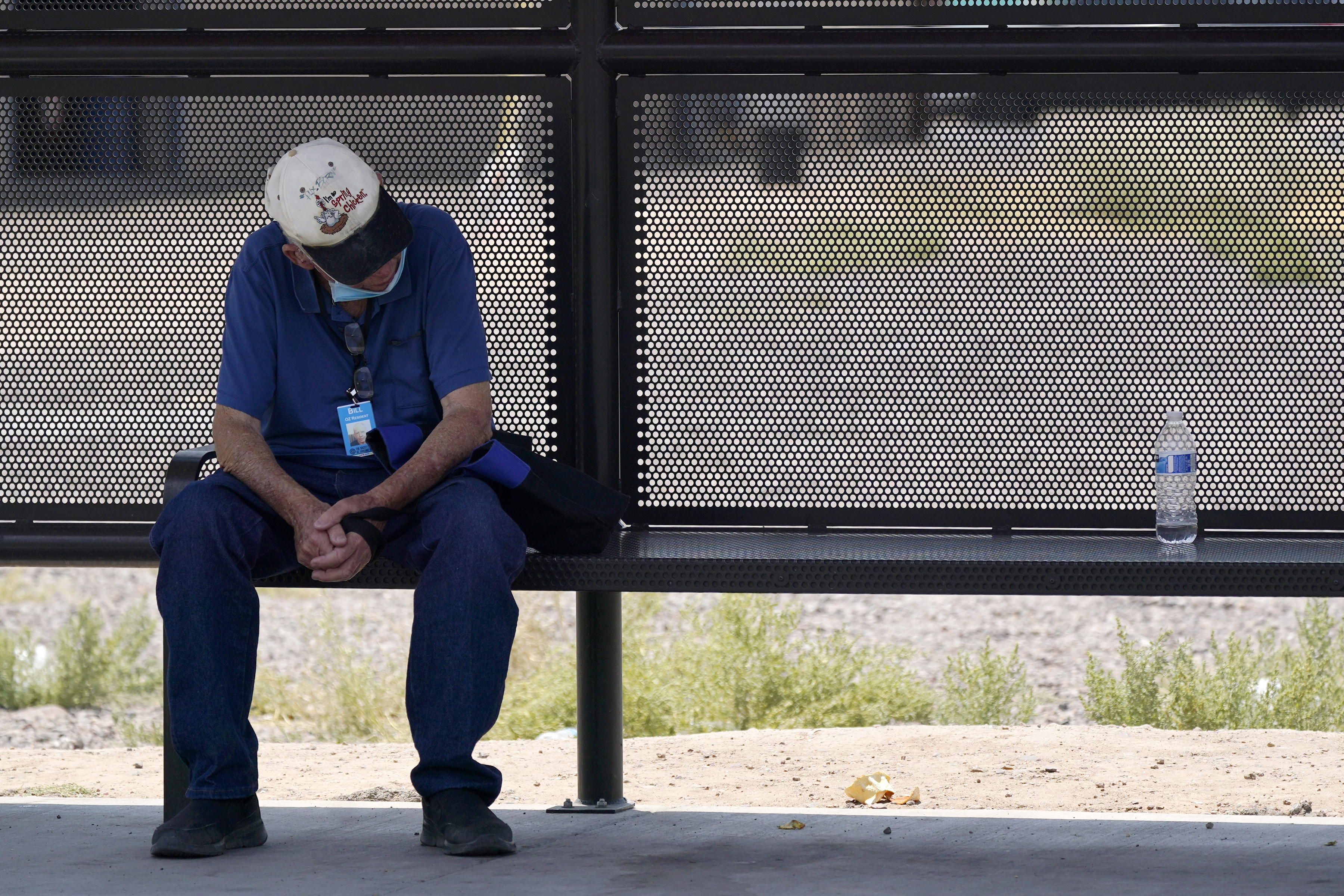 A person waits for a bus in the shade as the heat wave in the Western states continues Thursday, June 17, 2021, in Phoenix.