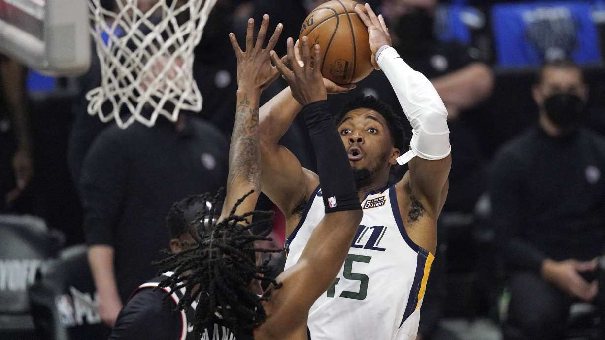 Utah Jazz guard Donovan Mitchell, right, shoots as Los Angeles Clippers guard Terance Mann defends during the first half in Game 6 of a second-round NBA basketball playoff series Friday, June 18, 2021, in Los Angeles.