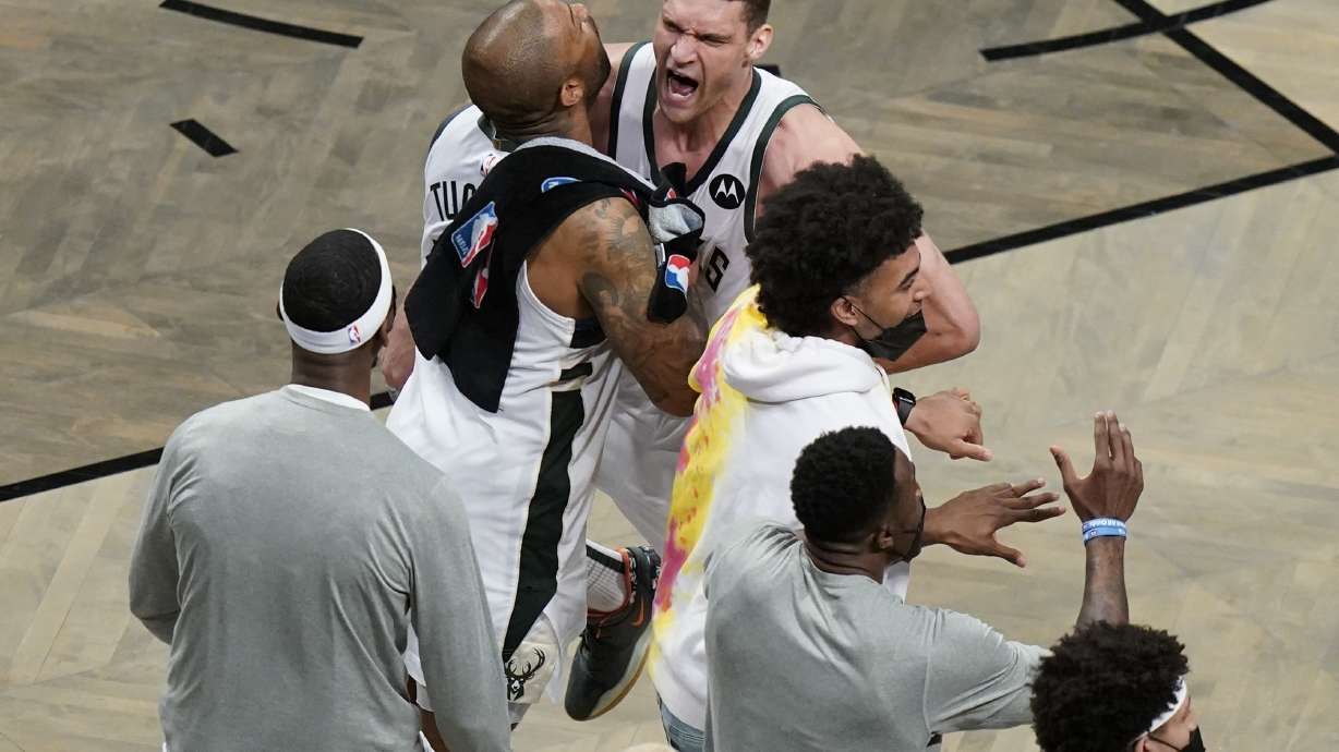 Milwaukee Bucks' Brook Lopez, right, celebrates with P.J. Tucker, left, and other teammates during overtime of Game 7 of a second-round NBA basketball playoff series Saturday, June 19, 2021, in New York.