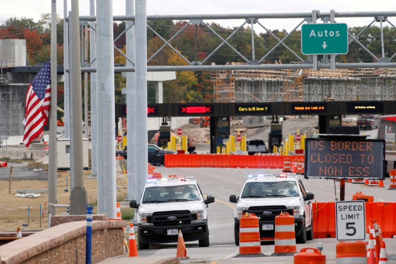 U.S. customs vehicles stand near a sign reading that the border is closed to non-essential traffic, at the Canada-United States border crossing at the Thousand Islands Bridge, to combat the spread of COVID-19 in Lansdowne, Ontario, Canada Sept. 28, 2020.