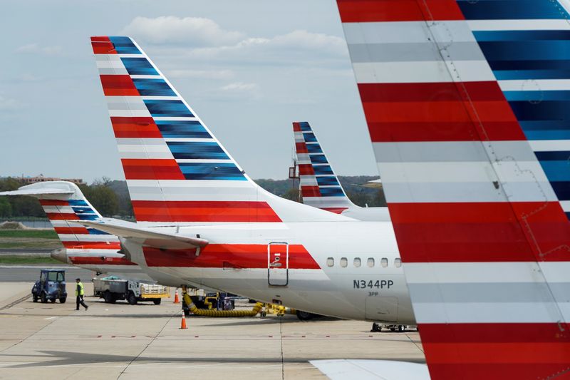 FILE PHOTO: A member of a ground crew walks past American Airlines planes parked at the gate at Ronald Reagan National Airport in Washington, U.S., April 5, 2020. The airline announced Sunday, June 20, 2021 that it would cancel around 1% of its flights in July.