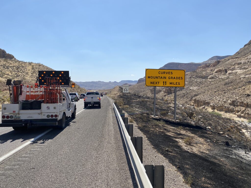 Arizona Department of Transportation trucks direct vehicles as they merge into one lane beside the burned patch of canyon, Virgin River Gorge, Arizona, June 20, 2021.