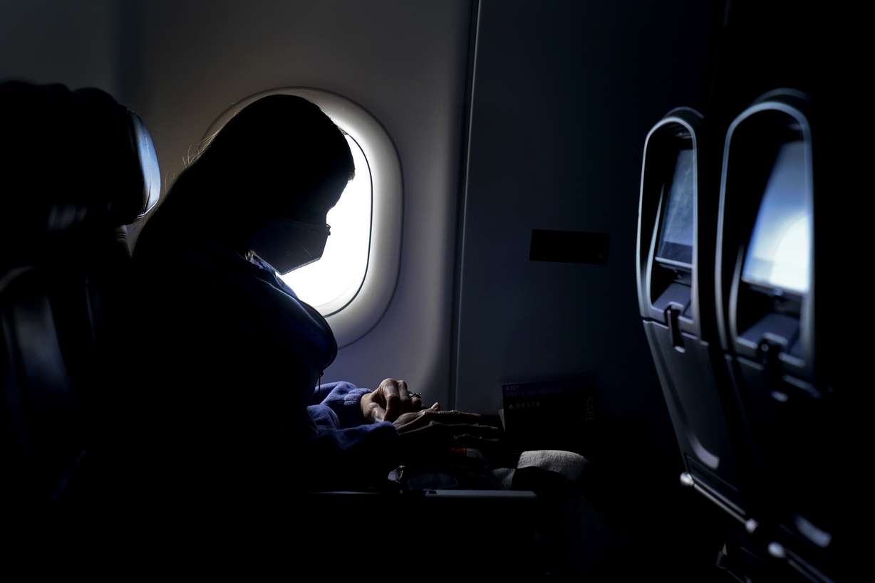A passenger wears a face mask she travels on a Delta Air Lines flight after taking off from Hartsfield-Jackson International Airport in Atlanta. Airlines have reported about 3,000 cases of disruptive passengers since Jan. 1, according to a spokesman for the Federal Aviation Administration.