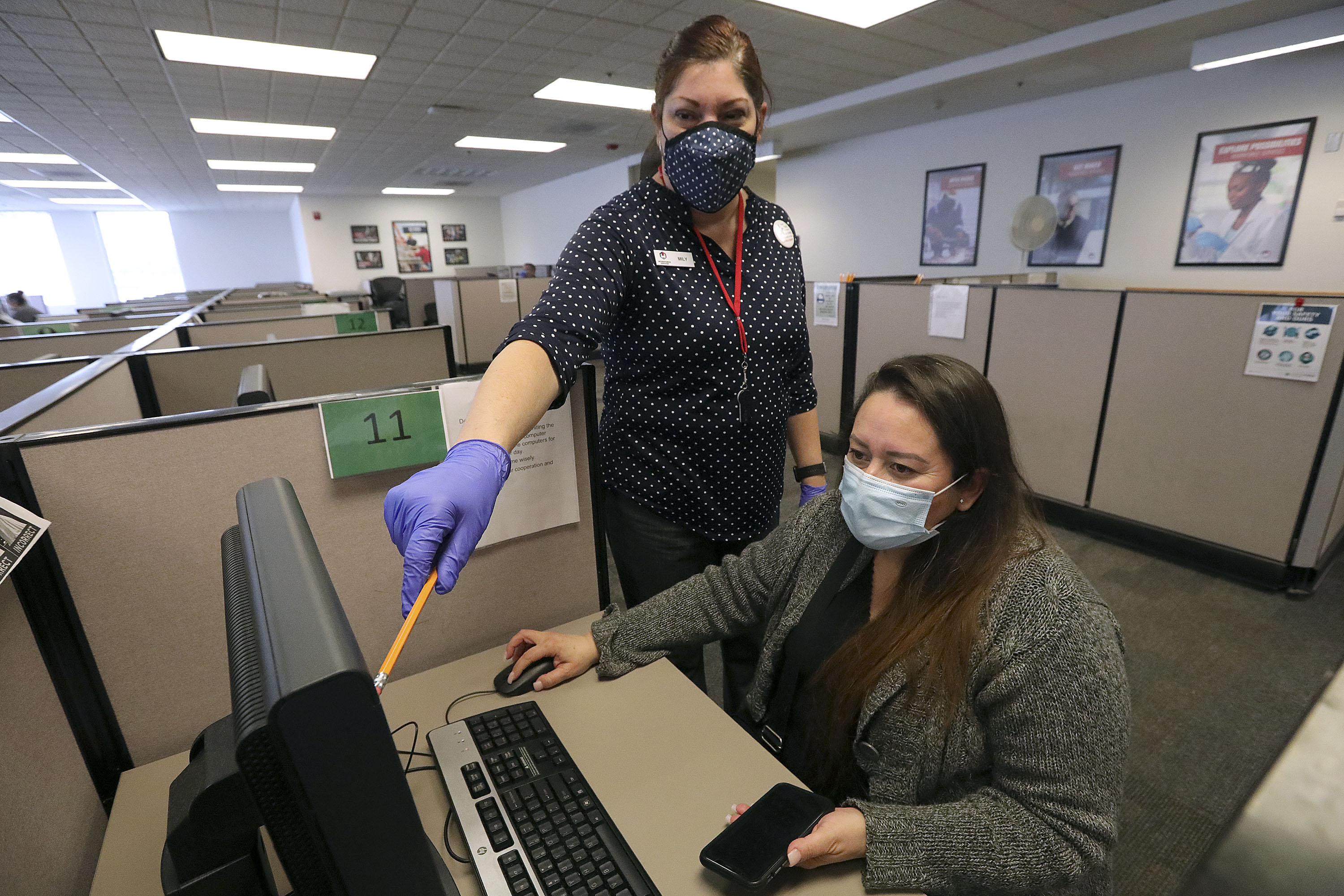 FILE: Mily Santos, Department of Workforce Services employment counselor, helps Glenda Morataya log in to apply for unemployment benefits at the Department of Workforce Services in Taylorsville on Thursday, April 15, 2021.