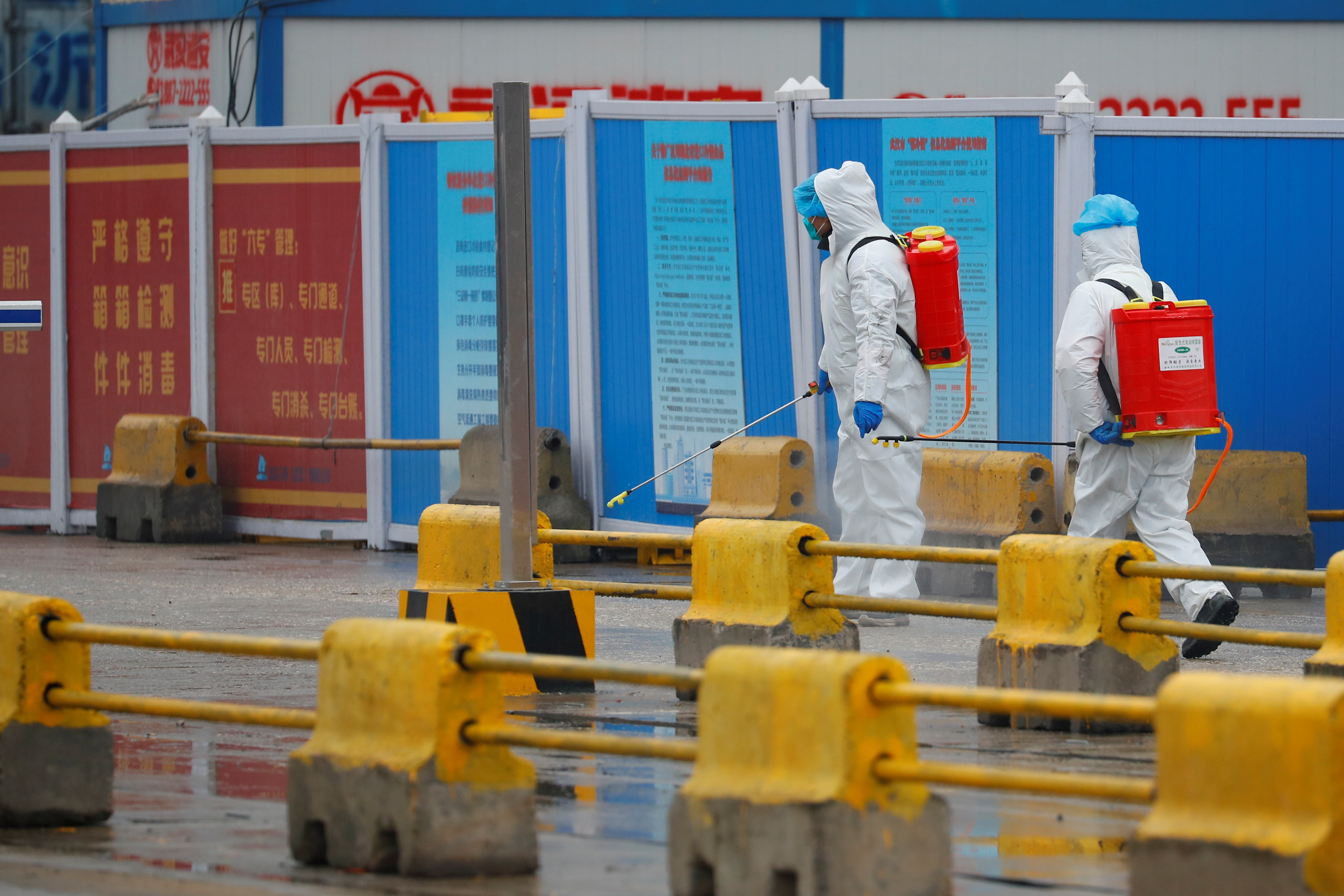 Workers in PPE spray the ground with disinfectant in Baishazhou market during a visit of World Health Organization team tasked with investigating the origins of the coronavirus pandemic, in Wuhan, Hubei province, China, Jan. 31, 2021. 