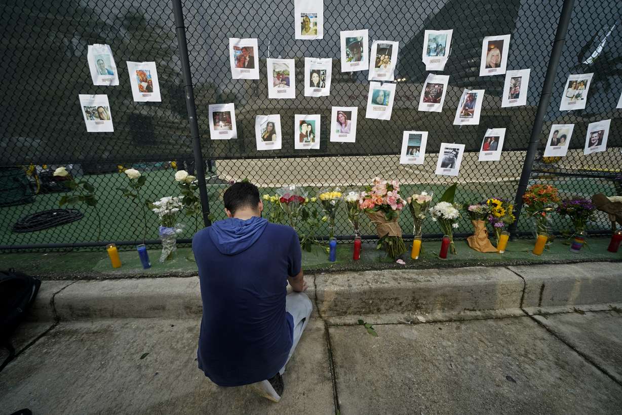 Leo Soto, who created this memorial with grocery stores donating flowers and candles, pauses in front of photos of some of the missing people that he put on a fence, near the site of an oceanfront condo building that partially collapsed in Surfside, Fla., Friday, June 25, 2021.