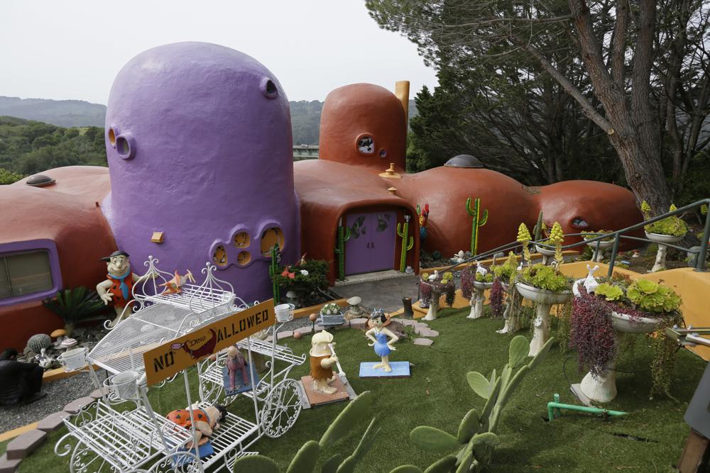 In this Thursday, April 11, 2019, file photo, The Flintstone House is seen before a news conference with the owner and the home's original architect in Hillsborough, Calif. The San Francisco Bay Area suburb of Hillsborough is suing the owner of the house, saying that she installed dangerous steps, dinosaurs and other Flintstone-era figurines without necessary permits.