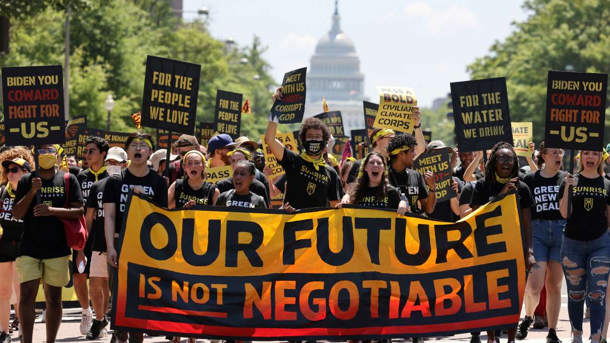 Demonstrators display signs and a banner during a "No Climate, No Deal" march on the White House, in Washington, D.C., on June 28, 2021.