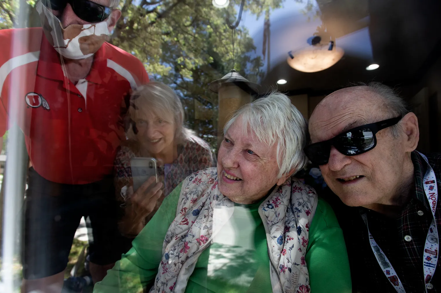 George and Nita Lutes speak through a window of their assisted living center in Millcreek with their nephew Tim Chambless and his wife, Cathy, on April 29, 2020. Now a bill before Congress seeks to let residents name “essential caregivers” who would not have to stay outside in a health crisis. 