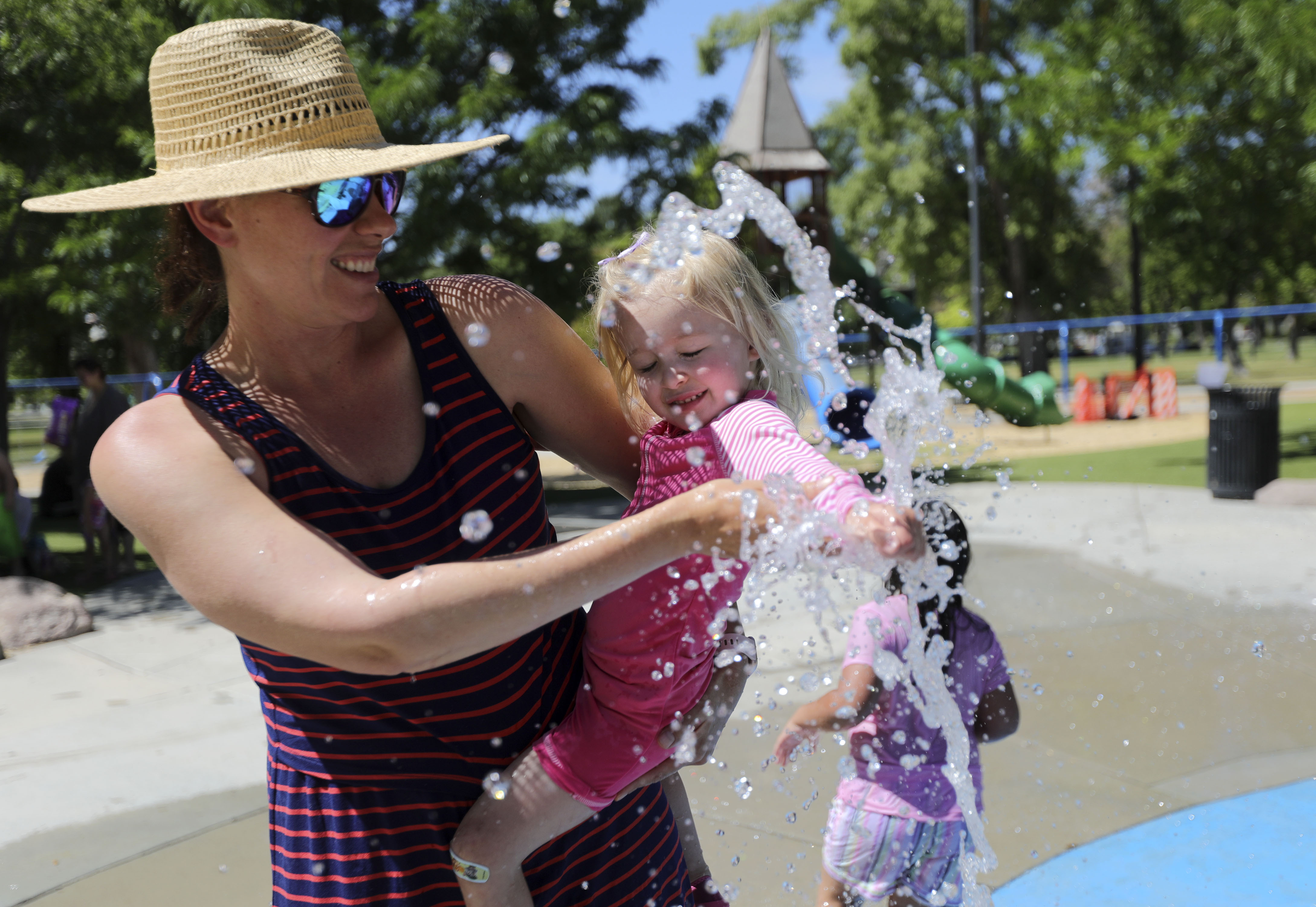 Kika Chelaru holds Bowie Walker as she tests out the water in the splash pad at Liberty Park during a heat wave in Salt Lake City on Monday, June 14, 2021. The National Weather Service said Thursday that June was the hottest on record in the 147 years it has kept track of Salt Lake weather.