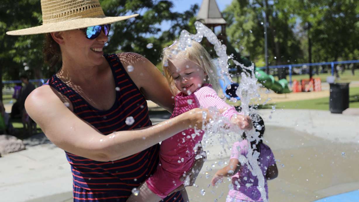 Kika Chelaru holds Bowie Walker as she tests out the water in the splash pad at Liberty Park during a heat wave in Salt Lake City on June 14, 2021. The National Oceanic and Atmospheric Administration's Center for Environmental Information reports 2021 was the third hottest on record in Utah.