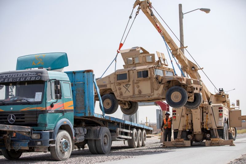 U.S. Army soldiers and contractors load High Mobility Multi-purposed Wheeled Vehicles, HUMVs, to be sent for transport as U.S. forces prepare for withdrawal, in Kandahar, Afghanistan, July 13, 2020.
