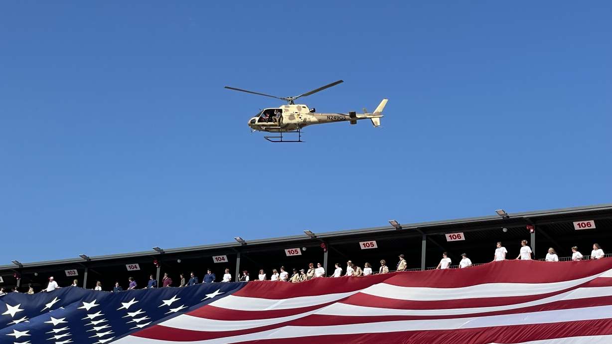 A helicopter carrying Gail Halvorsen, the Candy Bomber, flies over a U.S. flag in St. George on Saturday, July 3, 2021.