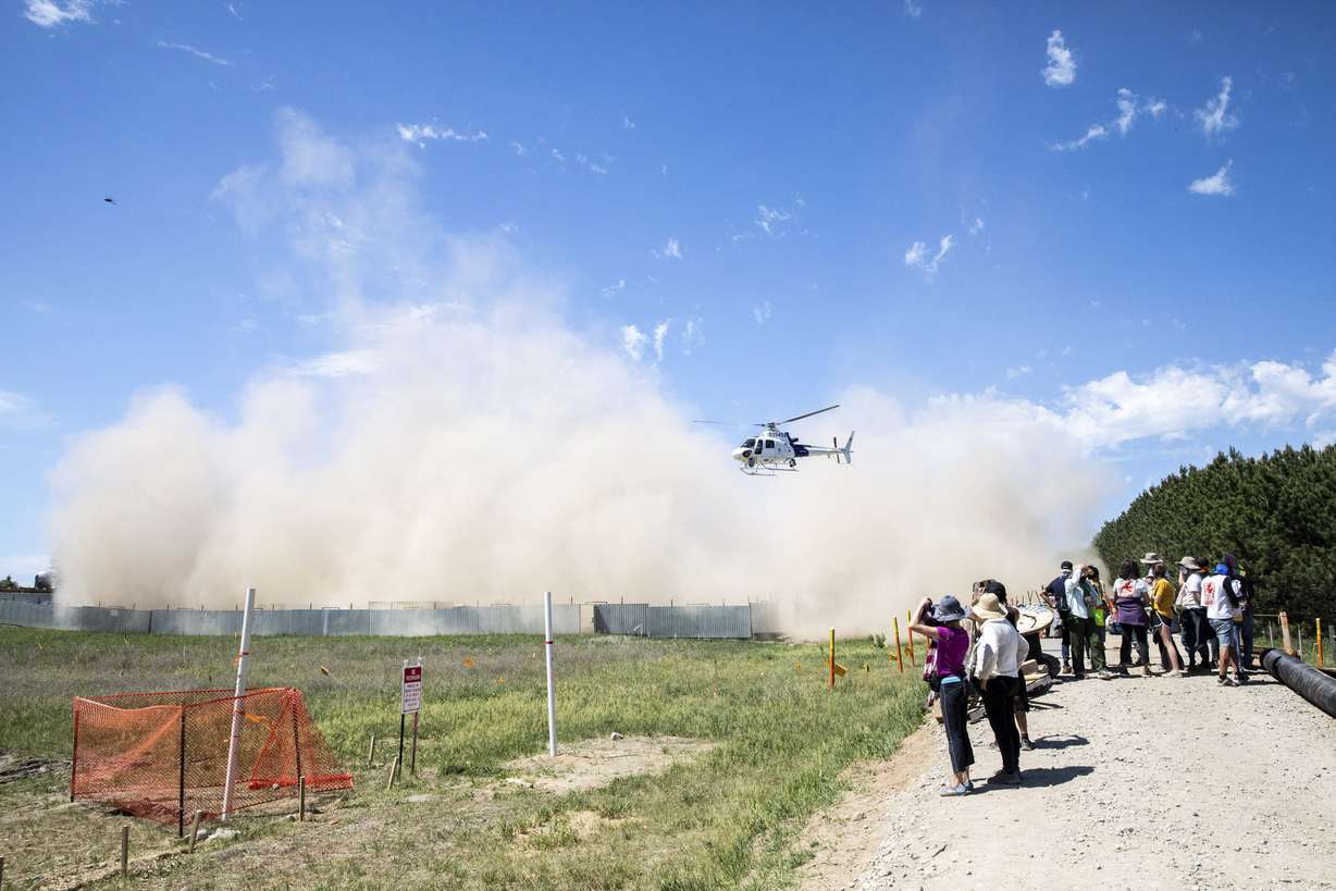 A Department of Homeland Security helicopter uses its rotor wash to stir up dirt as activists take materials to build barricades at an occupied Enbridge Line 3 pump station near Park Rapids, Minn. on June 7, 2021. Climate activists and their Democratic allies in Congress are pressing with renewed urgency for huge investments to slow global warming.