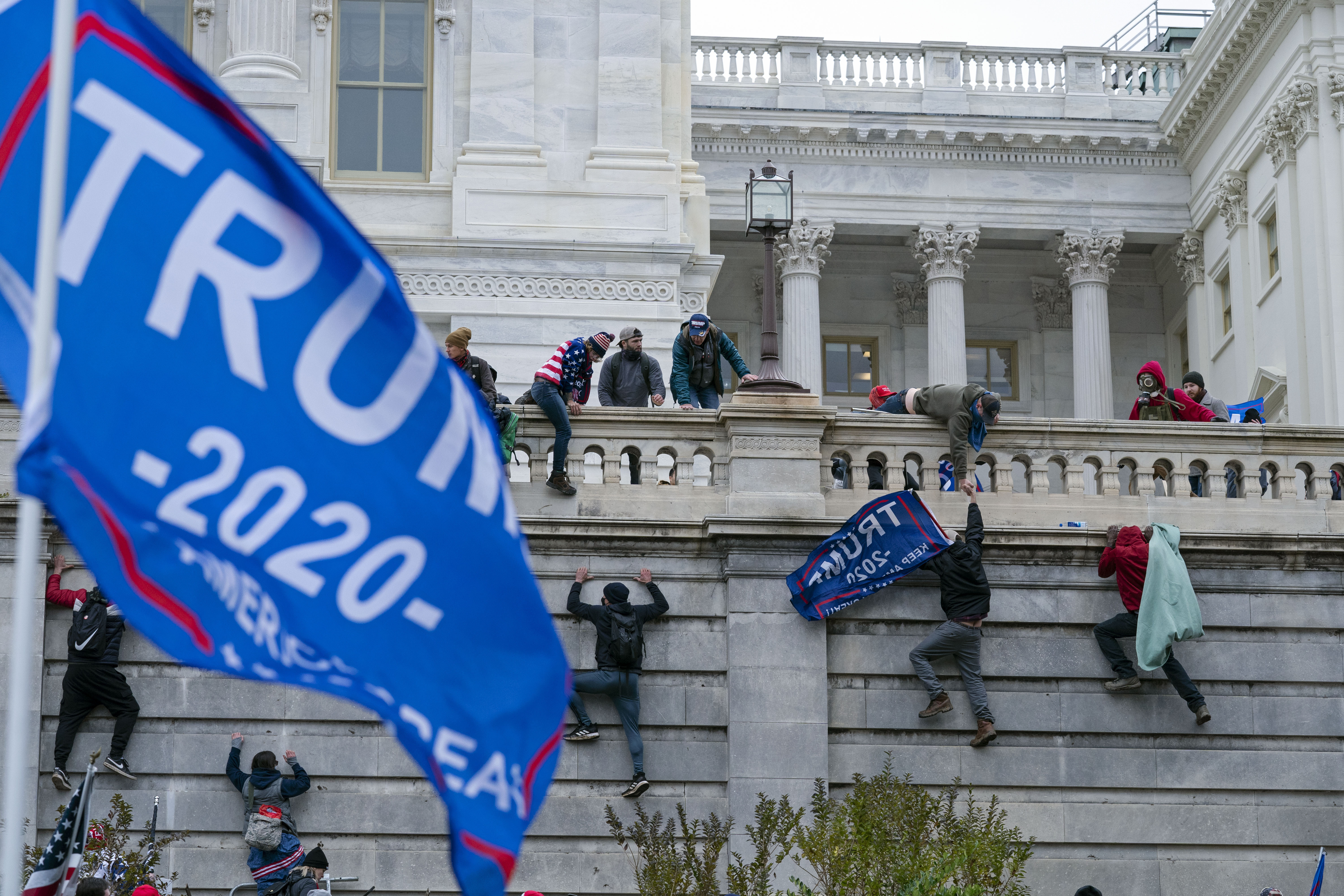 Rioters loyal to then-President Donald Trump climb the West Wall of the the U.S. Capitol in Washington. Even as the first of the more than 500 federal Capitol riot defendants have begun to plead guilty, scores of suspects remain unidentified, reflecting the massive scale of the Justice Department's investigation and the grueling work authorities still face to track everyone down.