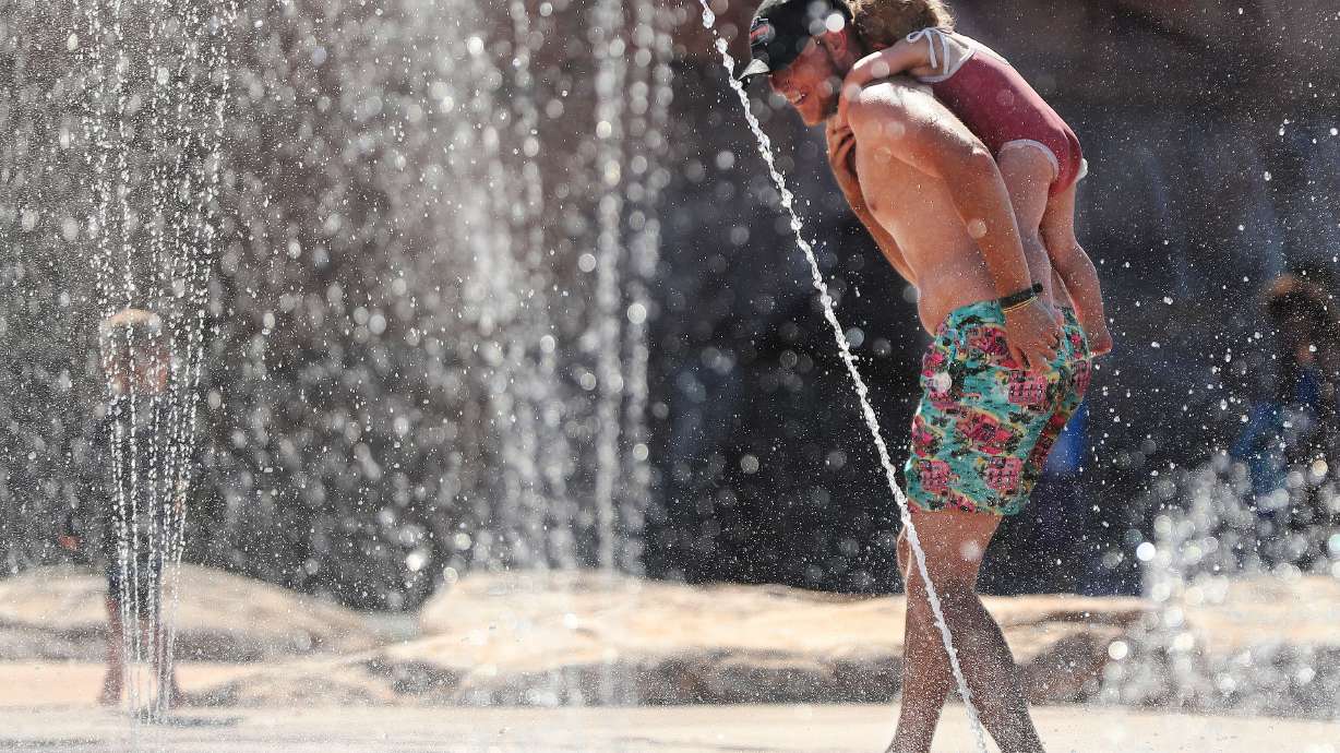 Brandan Sirrine runs in the water with daughter Blakley as they beat the heat at Wardle Fields Regional Park splash pad in Bluffdale on Thursday, June 3, 2021. Temperatures are expected are forecast to reach 100 degrees or more across most of Utah this week, prompting a new batch of heat warnings and advisories.