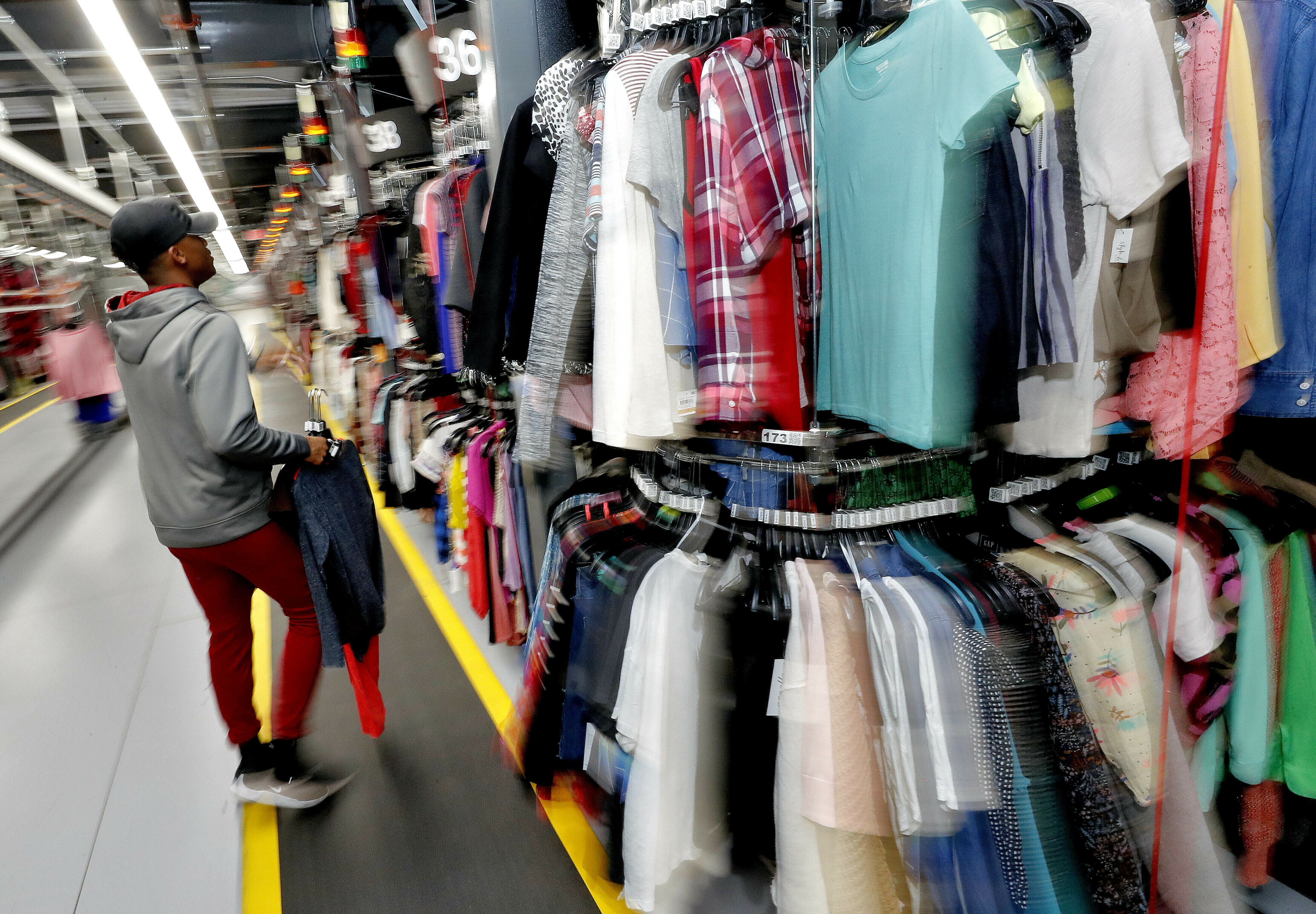 Willie Walton hangs clothing on a three-tiered conveyor system at the ThredUp sorting facility in Phoenix on March 12, 2019. A wardrobe purge is on for some people.