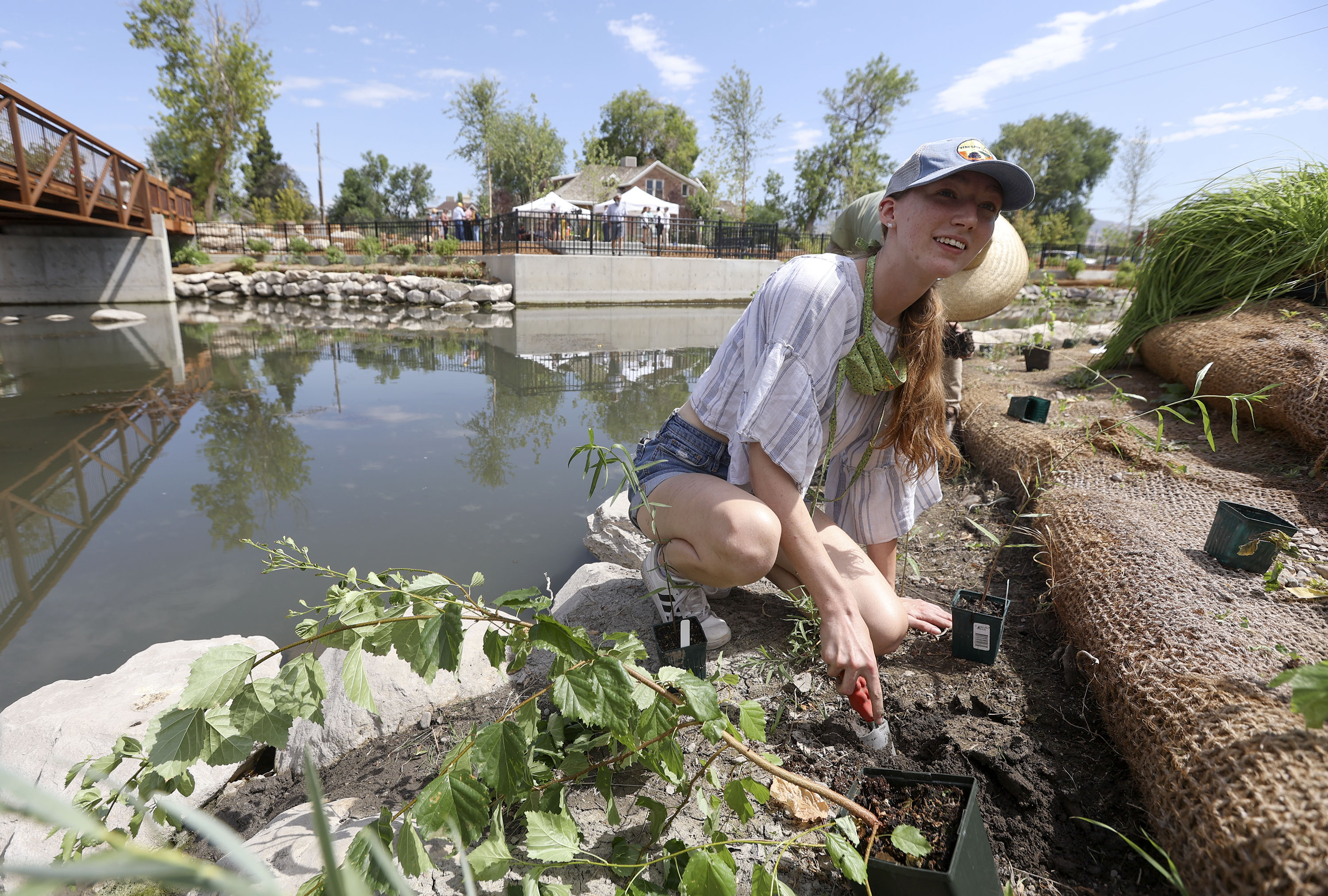 Madeline Houghton, Salt Lake City Trails and Natural Lands botanist intern, plants native shrubs, trees and flowers before a press conference to unveil the Three Creeks Confluence Park in Salt Lake City on Wednesday, July 7, 2021.