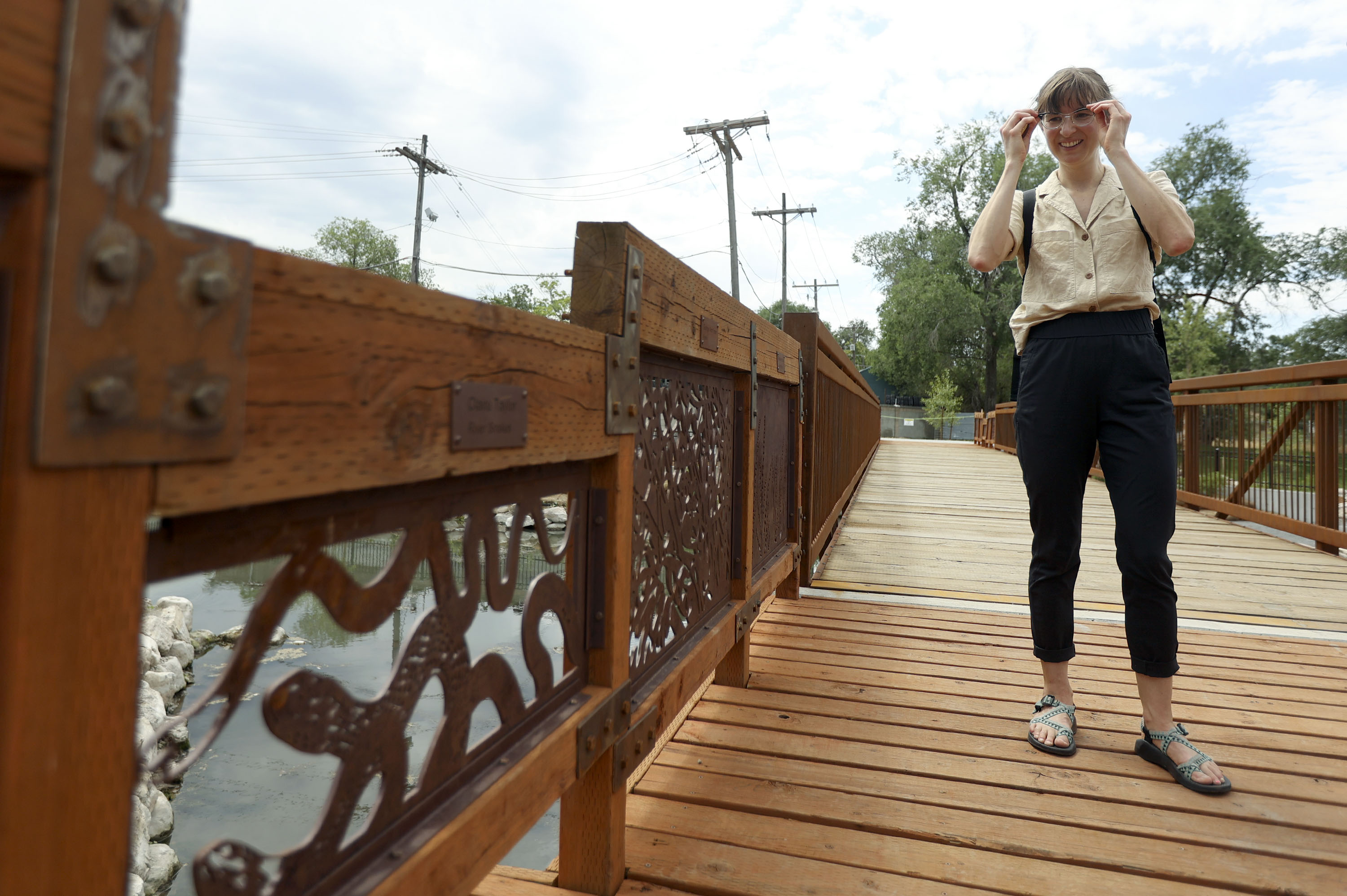 Claire Taylor looks at an installation of her artwork "River Snakes" on a bridge in the new Three Creeks Confluence Park in Salt Lake City on Wednesday, July 7, 2021. Each panel is by a different artist.