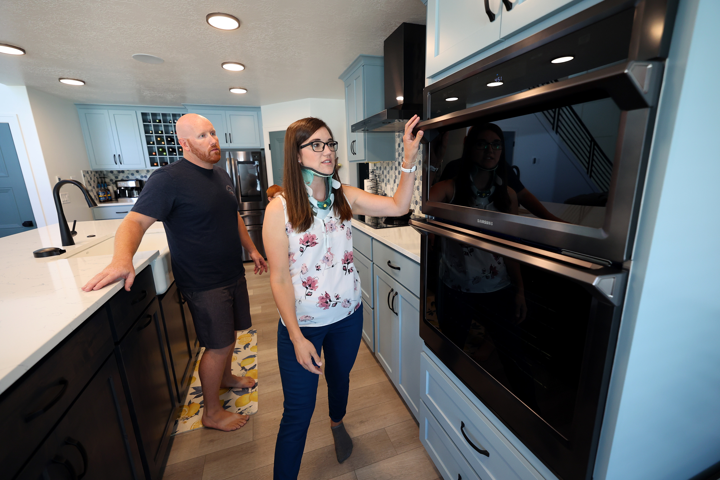Trevor Andersen watches as his wife, Brooke, points out items that make it easier for her to work in the kitchen of their Provo home on Wednesday, July 7, 2021. Brooke Andersen's spinal fusion surgery was delayed because of COVID-19 closures, but she finally made it to Spain during its brief opening window to have it. Now she can walk again, but she's still facing a lifetime of deterioration from her condition.