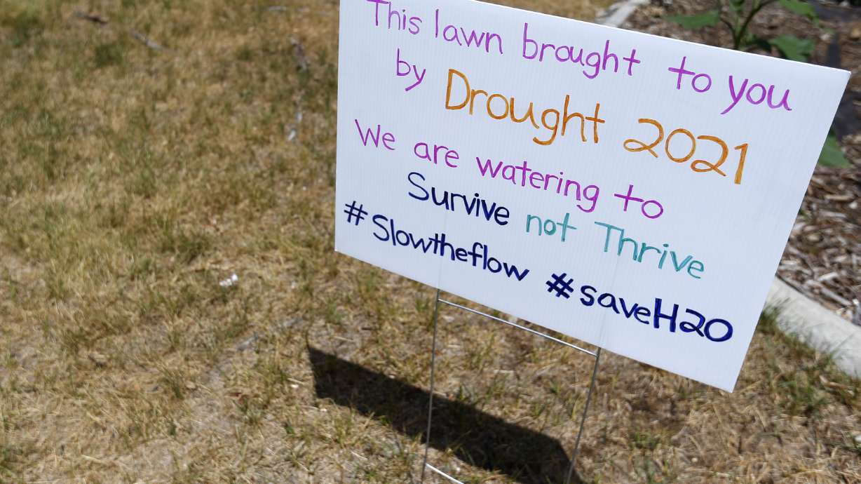 A sign in Emmalee Nelson Thompson’s Magna yard explains her decision not to water her lawn on Friday, July 2, 2021.