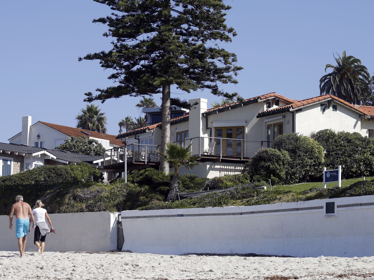 People walk along the beach in front of a home owned by Mitt Romney, and his wife Ann on Friday, Oct. 11, 2013, in La
Jolla, Calif. Romney has sold the oceanfront mansion — of car elevator fame — for a whopping $23.5 million.