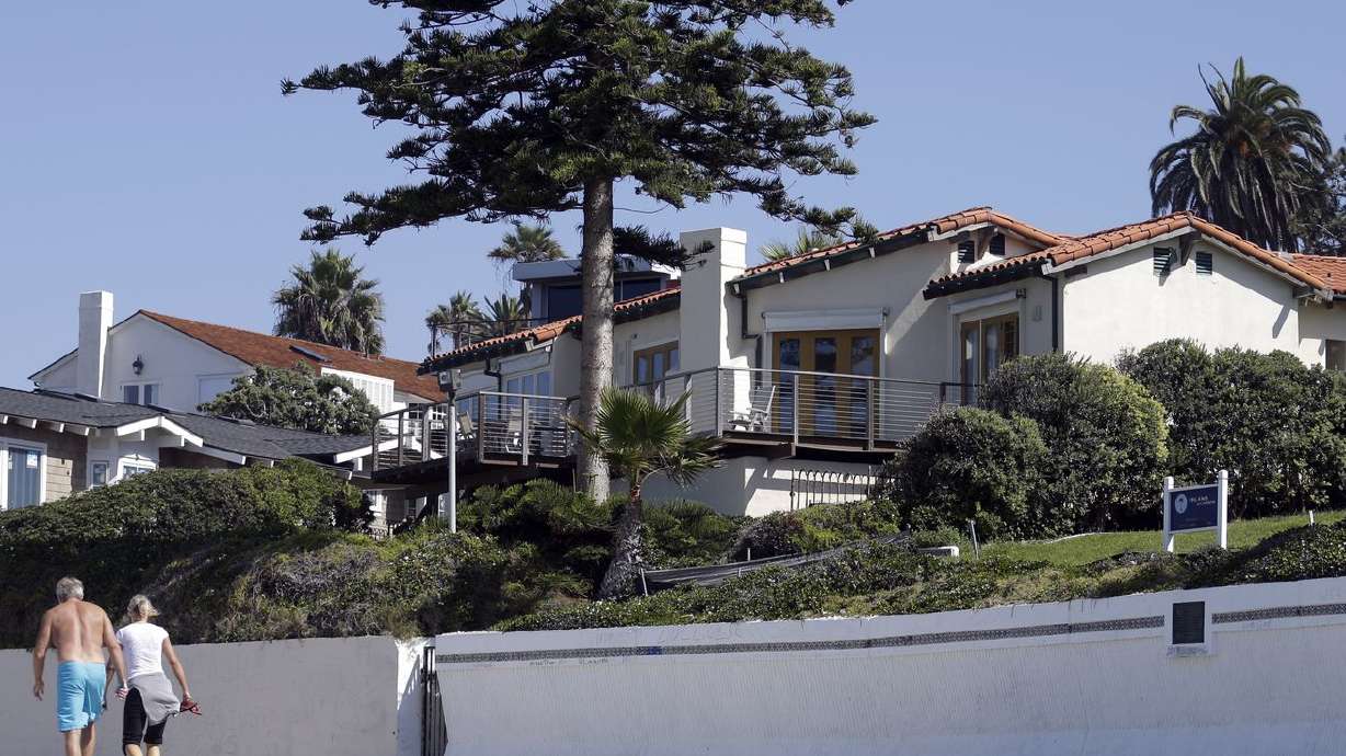 People walk along the beach in front of a home owned by Mitt Romney, and his wife Ann on Friday, Oct. 11, 2013, in La
Jolla, Calif. Romney has sold the oceanfront mansion — of car elevator fame — for a whopping $23.5 million.