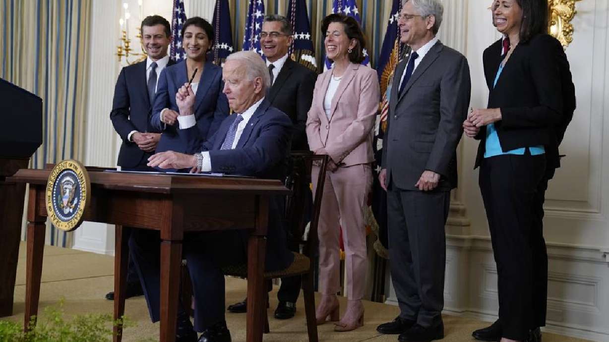 President Joe Biden hands out a pen after signing an executive order aimed at promoting competition in the economy, in the State Dining Room of the White House, Friday, July 9, 2021, in Washington. Standing from left, Transportation Secretary Pete Buttigieg, Lina Khan, Chair of the Federal Trade Commission, Health and Human Services Secretary Xavier Becerra, Commerce Secretary Gina Raimondo, Attorney General Merrick Garland, National Economic Council director Brian Deese, obscured, and Jessica Rosenworcel, Acting Chairwoman of the Federal Communications Commission.