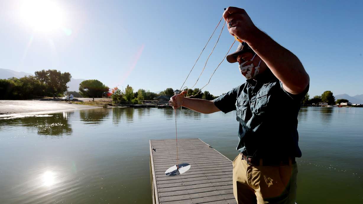 Ryan Van Goethem of SePro demonstrates the use of a Secchi disk to measure the water clarity as the company works to treat an algal bloom at Utah Lake on Friday, Sept. 4, 2020.