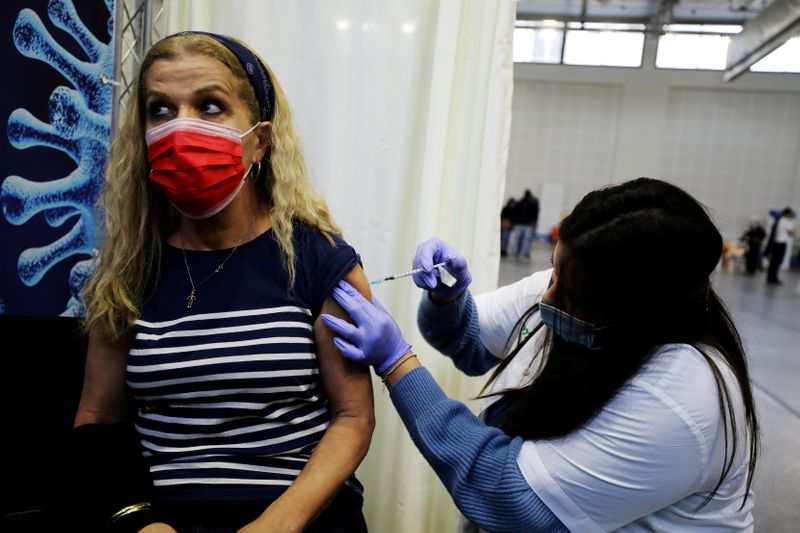 FILE PHOTO: A woman receives a vaccination against the coronavirus disease (COVID-19) at a temporary Clalit healthcare maintenance organisation (HMO) centre, at a basketball court in Petah Tikva, Israel January 28, 2021.