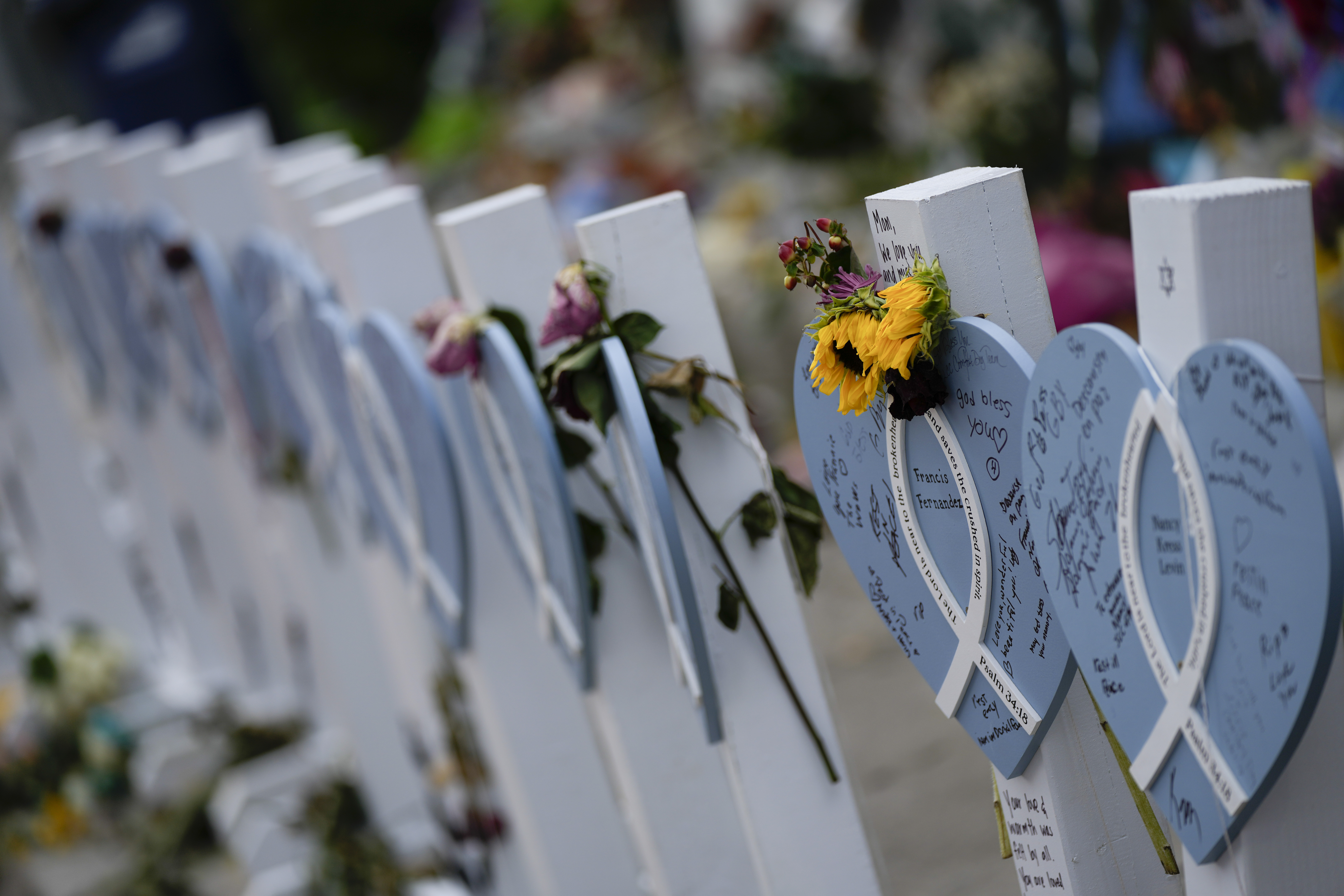 Flowers and messages of love adorn wooden hearts with the names of victims of the Champlain Towers South building collapse, at a makeshift memorial near the site, on Monday, July 12, 2021, in Surfside, Fla.