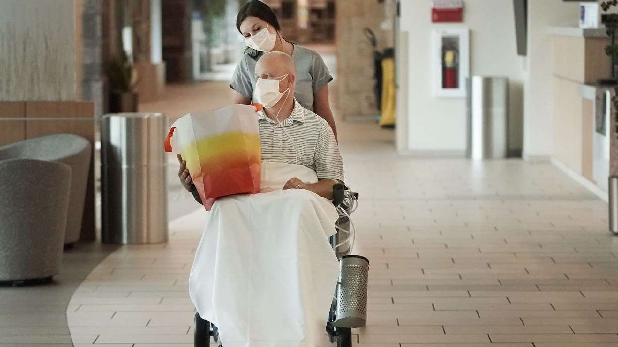 Nurse practitioner Aaron Hartle is wheeled out of Utah Valley Hospital by Haley Dunn after being released in Provo on
Sunday, July 11, 2021. Hartle was hospitalized with COVID-19 after turning down the vaccine and now wants to urge others to get the shots.