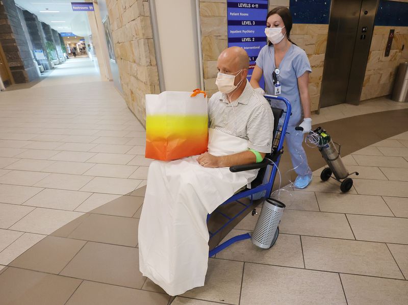 Nurse practitioner Aaron Hartle is wheeled out of Utah
Valley Hospital by Haley Dunn after being released in Provo on
Sunday, July 11, 2021. Hartle was hospitalized with COVID-19 after
turning down the vaccine and now wants to urge others to get the
shots.