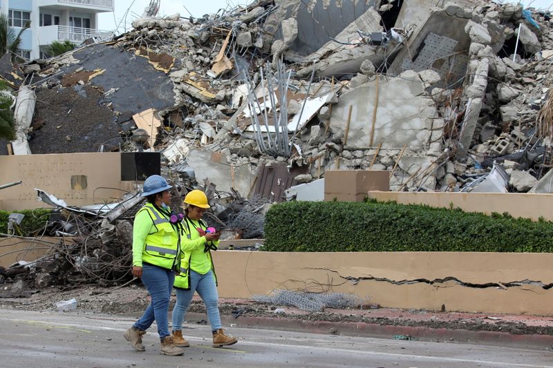 Rescue workers walk past debris after the managed demolition of the remaining part of Champlain Towers South complex as search-and-rescue efforts continue in Surfside, Florida, U.S. July 6, 2021.
