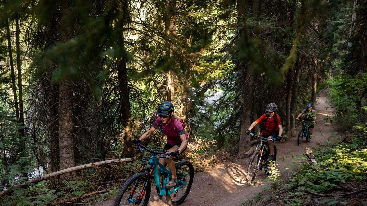 Heather King, left, and Michael King, right, and their son, Seth, 14, ride mountain bikes on the Big Water Trail in Millcreek Canyon on Monday, July 12, 2021.
