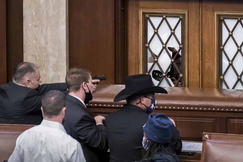 In this Jan. 6, 2021 file photo, security agents and lawmakers barricade the door to the House chamber as violent mob loyal to then-President Donald Trump, breached the Capitol in Washington and disrupted the Electoral College process. Key figures in the Jan. 6 riot on U.S. Capitol spoke about their desire to overthrow the government, but to date, U.S prosecutors have charged no one with sedition. They could still add them. But prosecutors may be reluctant to bring them because of their legal complexity and the difficulty in securing convictions.
