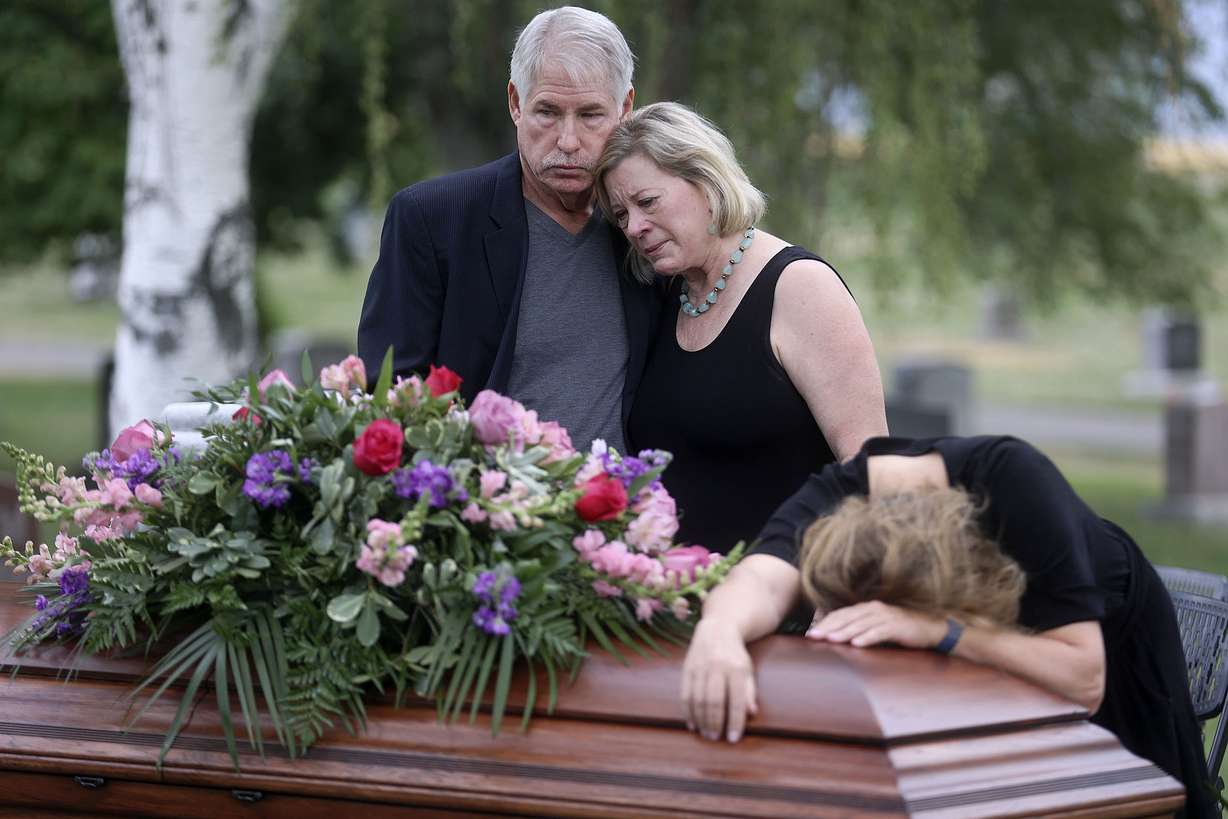 Clark Knighton and Shari Knighton hug as Tricia Wright weeps over the casket of Shari and Tricia's sister, Shawna Wright, who died of heat exhaustion while homeless, during Shawna Wright's interment at Mount Olivet Cemetery in Salt Lake City on Tuesday, July 13, 2021.
