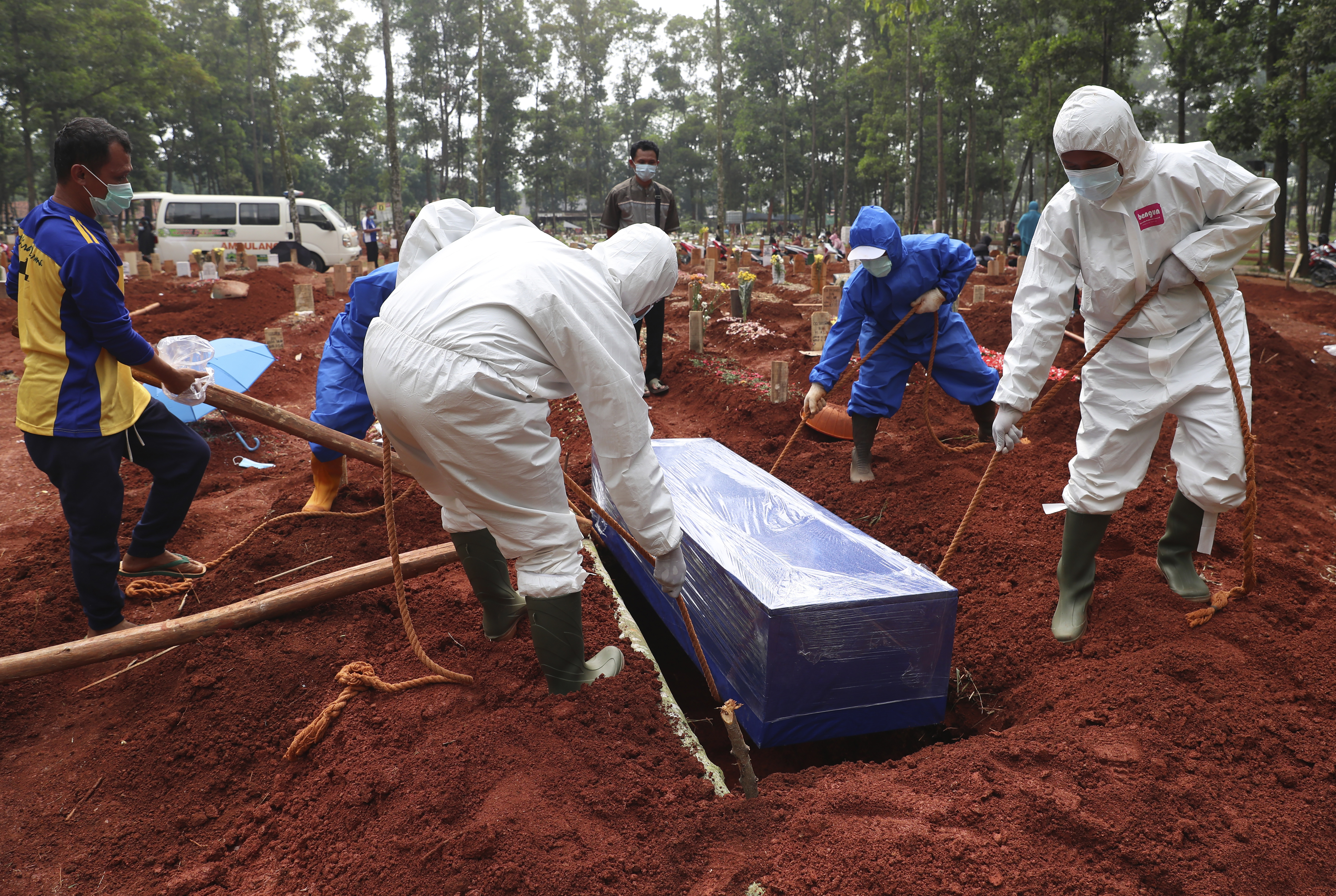 Workers in protective gear lower a coffin of a COVID-19 victim to a grave for burial at the Cipenjo Cemetery in Bogor, West Java, Indonesia, Wednesday, July 14, 2021. The world's fourth most populous country has been hit hard by an explosion of COVID-19 cases that have strained hospitals on the main island of Java. 
