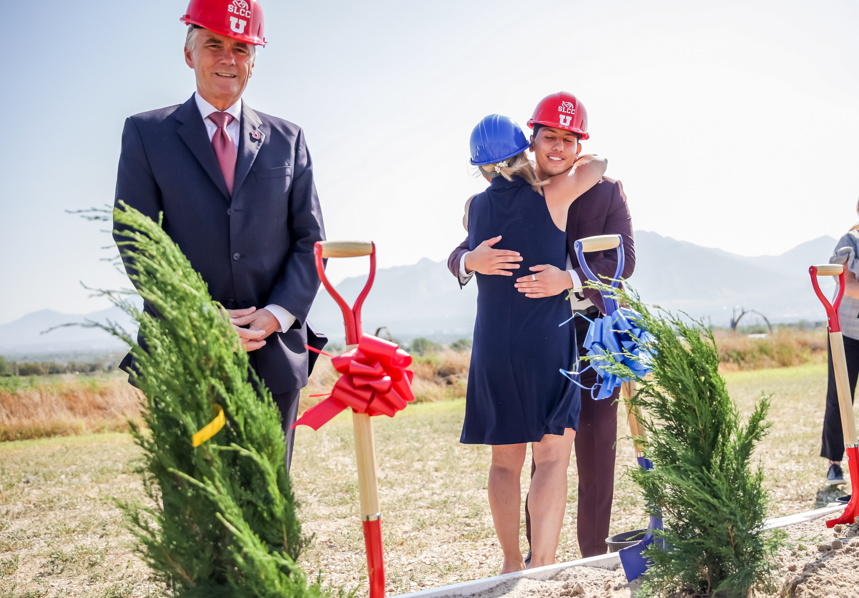 Salt Lake Community College President Deneece Huftalin, center, hugs Alvaro Martinez, a SLCC alum who is now attending the University of Utah, while U. interim President Dr. Michael Good, left, stands by during a groundbreaking ceremony for the Juniper Canyon Campus in Herriman on Thursday, July 15, 2021. The campus is a new partnership between the U. and SLCC.