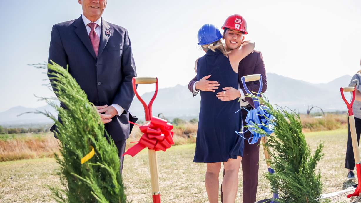 Salt Lake Community College President Deneece Huftalin, center, hugs Alvaro Martinez, a SLCC alum who is now attending the University of Utah, while U. interim President Dr. Michael Good, left, stands by during a groundbreaking ceremony for the Juniper Canyon Campus in Herriman on Thursday, July 15, 2021. The campus is a new partnership between the U. and SLCC.