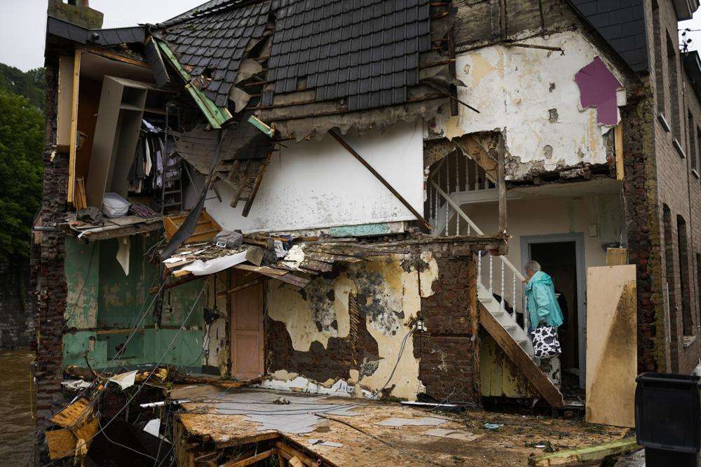 A woman walks up the stairs in her damaged house after flooding in Ensival, Vervier, Belgium, Friday July 16, 2021. Severe flooding in Germany and Belgium has turned streams and streets into raging torrents that have swept away cars and caused houses to collapse.