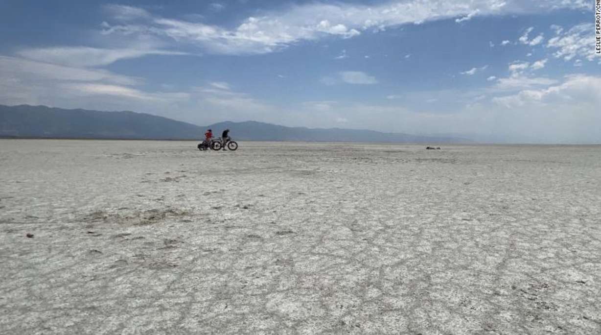 Lucy Kafanov of CNN and Kevin Perry ride bikes Tuesday on the dry lake bed playa of the Great Salt Lake.