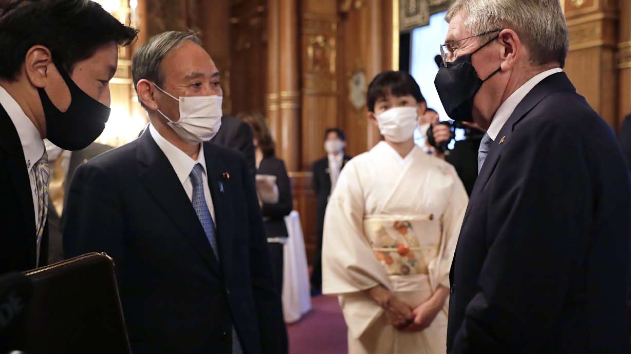 IOC President Thomas Bach, right, meets with Japanese Prime Minister Yoshihide Suga, second from left, during a welcome party for Bach and IOC officials at Akasaka Palace, Japanese state guest house, in Tokyo, Japan, Sunday, July 18, 2021.