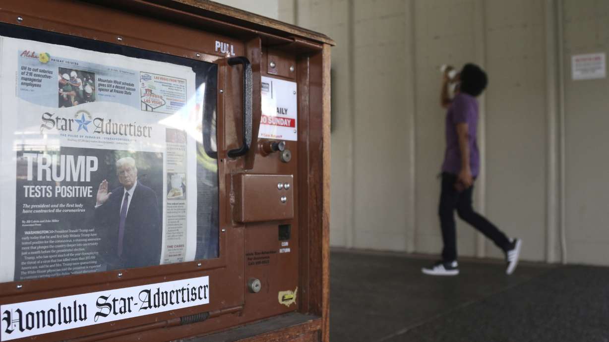 A man walks past a newspaper stand at the international airport in Honolulu on Friday, Oct. 2, 2020. The coronavirus pandemic, a high-stakes U.S. election, and a racial reckoning expanded news audiences for many newspapers and TV news channels, but it was terrible for the newspaper industry’s finances.