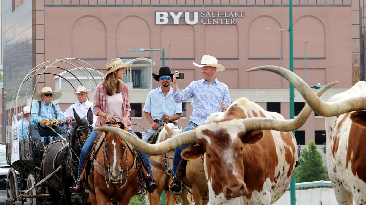 Gov. Spencer Cox, right, takes video as he, first lady Abby Cox and others drive a small herd of Texas longhorn cattle along North Temple toward the Utah State Fairpark in Salt Lake City on Monday, July 19, 2021. The drive was held to celebrate the return of the Days of ‘47 Cowboy Games and Rodeo.