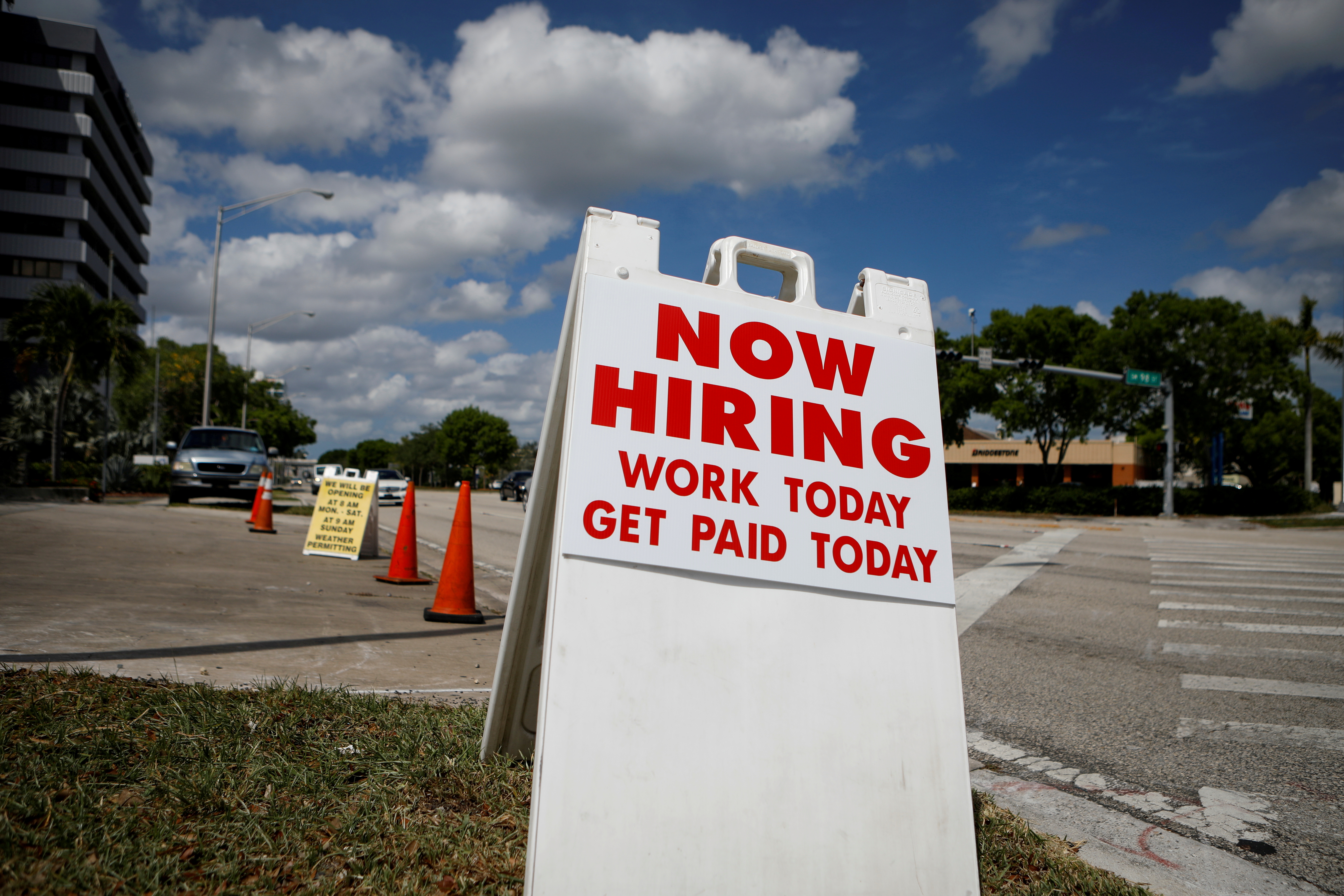A "Now Hiring" sign advertising jobs at a hand car wash is seen along a street in Miami. May 8, 2020. States putting an early end to federal unemployment benefits saw a larger jump in local labor supply in June than those planning to maintain the $300 weekly supplement until early September, new data show.