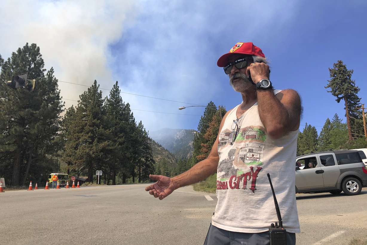 Tony Galvez, who lost his home to the Tamarack Fire, talks on his phone with his daughter in Vermont who's setting up a GoFundMe for him as he waved and clapped at passing firefighters in Woodfords, Calif., on Tuesday, July 20, 2021.