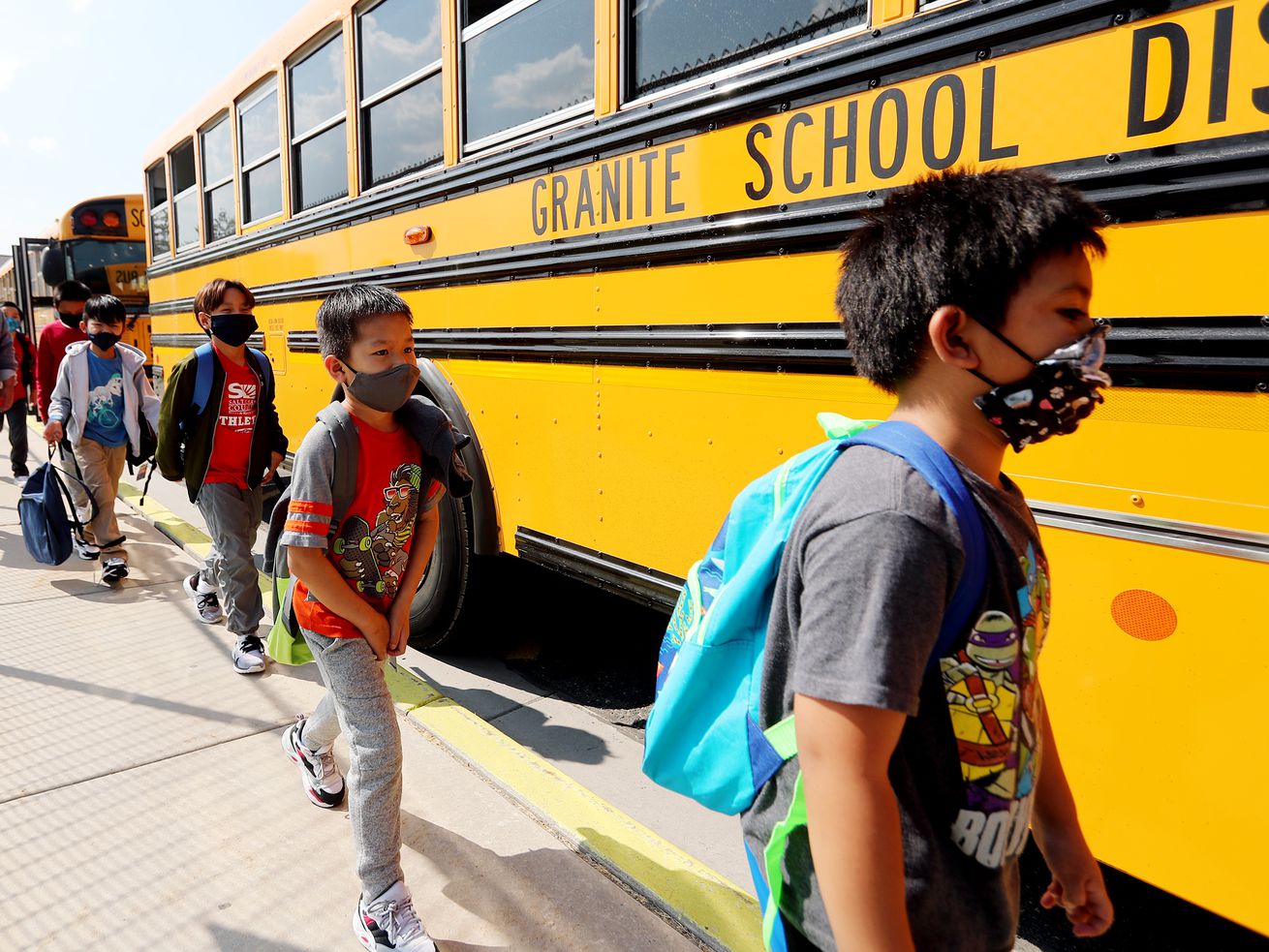 Students at Woodrow Wilson Elementary School in South Salt Lake wear masks as they get on a bus to go home after their first day of school on Monday, Aug. 24, 2020. School districts are announcing their policies for returning to class this fall.