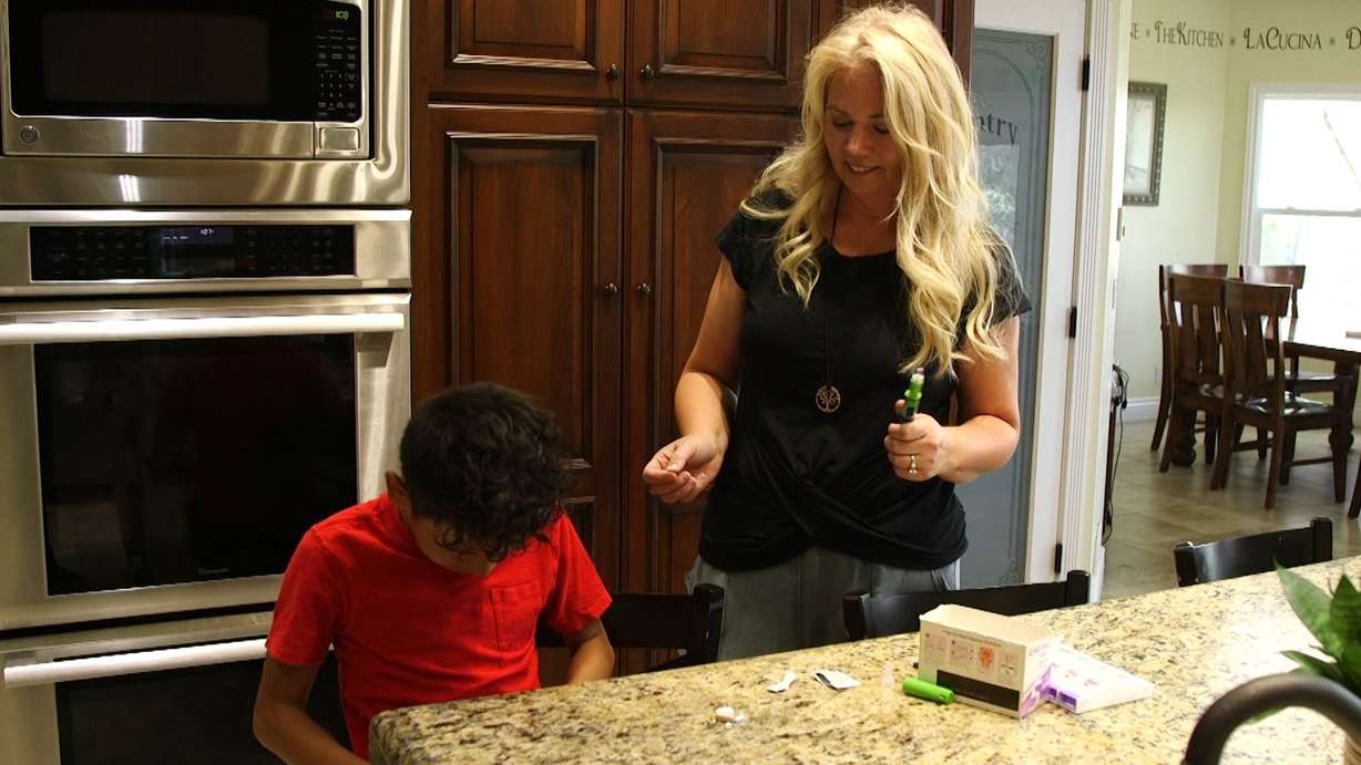Rachel Thorell helps her son, Garrett Thorell, administer a daily shot to help with some of the side effects he deals from his treatment.
