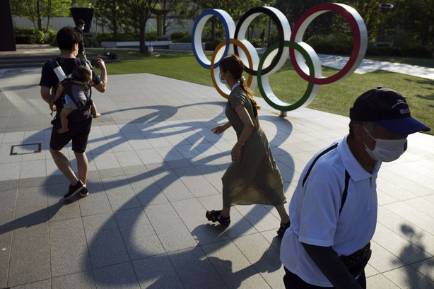 People walk near the Olympic Rings on Wednesday, June
9, 2021 in Tokyo.